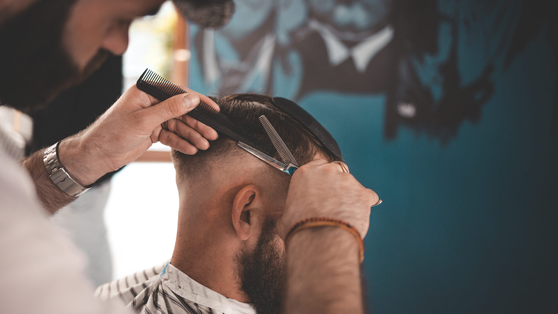 Stylish hairdresser in a cap does a haircut